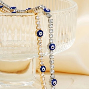 Detail of tennis bracelets with sparkling square zircons and blue evil eye charms