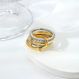 Dettaglio di anelli sovrapposti in oro e argento con pavé di zirconi su base in pietra