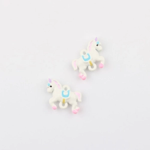 Close-up of white enamel unicorn charms with pink mane and blue saddle for DIY jewelry