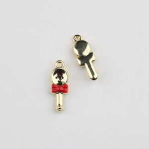 Makroaufnahme von Löffel-Anhänger mit roter Emaille-Schleife und goldener Legierung