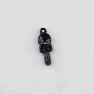 Detail of black cartoon spoon pendant with a smile face and bow for DIY jewelry making