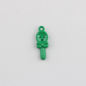 Detailed view of a green cartoon spoon pendant with a smiley face and bow for DIY jewelry