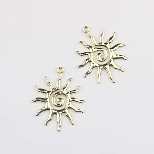Macro detail of sunburst spiral alloy charms in gold finish for DIY jewelry
