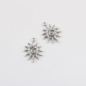 Macro detail of two silver sun pendants with textured hammer finish and spiral center