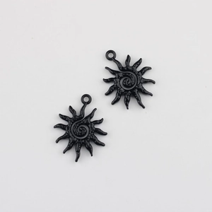 Macro detail of black sunflower charms with spiral centers and rings for DIY jewelry