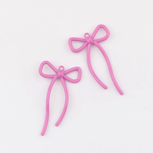 Detalle de dos colgantes de lazo en aleación rosa con acabado pintado para joyería DIY