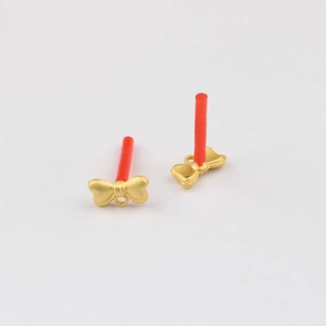Macro detail of matte gold bow-shaped jewelry pendants with small rings for DIY crafts