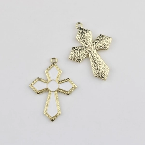 Détail de pendentifs croix en émail blanc avec motifs floraux dorés et anneaux de fixation
