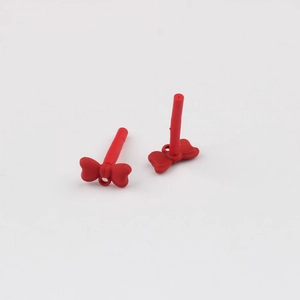 Macro detail of red bow-shaped DIY jewelry charms with matte finish and back pin