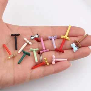 Micro bow alloy charms in colorful macaron shades held in hand to show small size