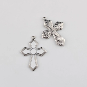 Détail macro du pendentif croix avec face en émail blanc et dos en métal texturé poli