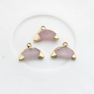 Détail de trois pendentifs demi-lune en pierre naturelle rose avec bordure dorée