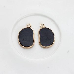 Macro shot of irregular black agate pendant with smooth gold plating and top hanging loop