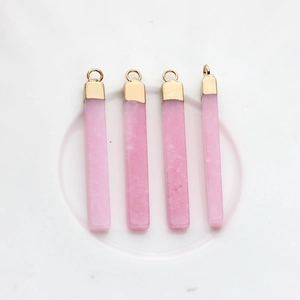 Vista macro di quattro ciondoli in quarzo rosa con eleganti cappucci e anelli placcati oro