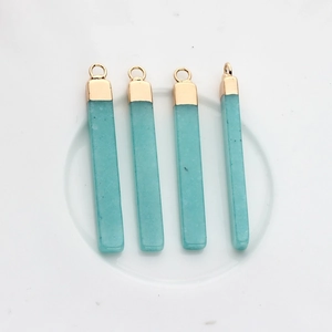 Dettaglio di pendenti geometrici in pietra naturale blu-verde con cappucci dorati
