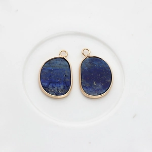 Detail of natural Lapis Lazuli stone charms with irregular gold-plated edging