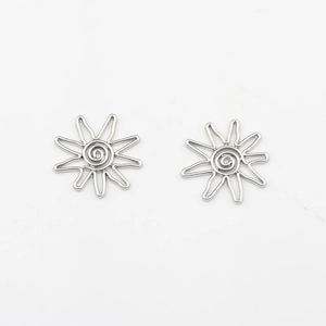 Detail of silver sun-shaped geometric earrings featuring swirl centers and wavy rays