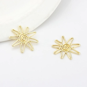 Detailed view of two gold sun-shaped hollow pendants on a white ceramic tray