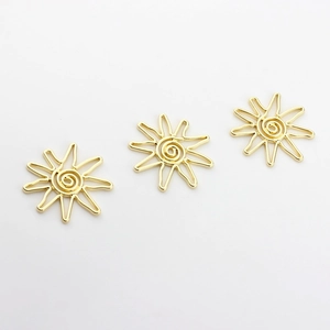 Macro detail of three golden hollow sunburst charms with spiral centers for DIY jewelry