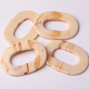Macro shot of oval resin jewelry charms with beige amber marble texture for DIY making