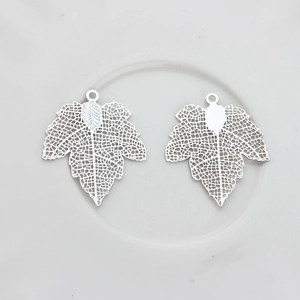 Macro view of silver hollow maple leaf charms with intricate filigree details for DIY jewelry