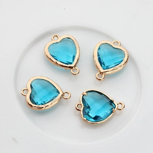 Close-up of four sky blue heart-shaped crystal charms with gold-plated copper frames