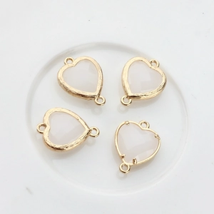 Macro detail of heart-shaped crystal pendants with dual golden metal loops for DIY jewelry