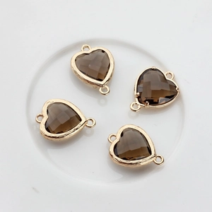 Close-up of four smoky faceted crystal heart charms with gold-plated copper frames