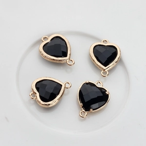 Close-up of four faceted black heart crystals with gold plated edges for DIY jewelry