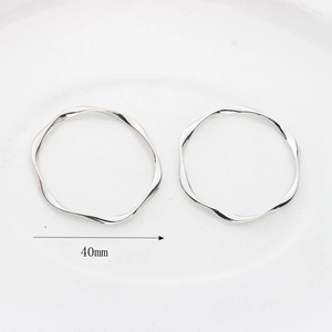 Detail of silver wavy hoop earrings featuring 40mm diameter with twisted metal texture