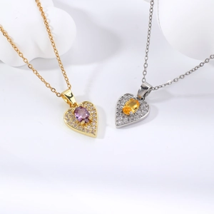 Détail de pendentifs en forme de cœur avec pierres violettes et jaunes sur chaînes or et argent