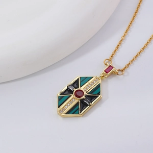 Close-up of hexagonal gold pendant with green enamel and red center stone necklace