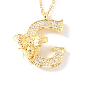 Dettaglio del ciondolo a lettera C dorata con zirconi micro-pavé e piccola ape decorativa