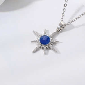 Macro shot of silver starburst pendant with dark blue center stone and zircon detailing