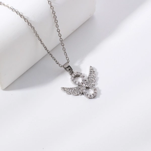 Silver infinity wing pendant necklace with cubic zirconia on a white stone pedestal