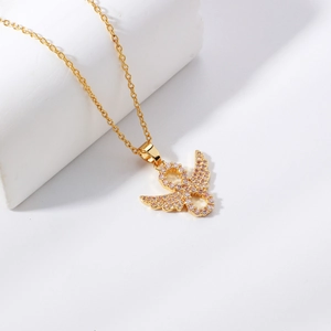 Golden angel wing pendant necklace with pink zircon stones on white background