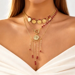 Détail du collier doré multi-rangs orné de perles rouges, pièces et chaînes à franges