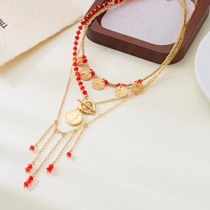 Détail du collier à plusieurs rangs avec pièces dorées, perles rouges et médaillons