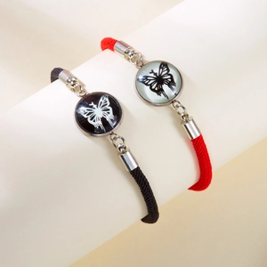 Detail of hand-woven sun and moon couple bracelets with butterfly glass pendants