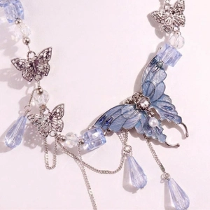 Detailansicht eines blauen Emaille-Schmetterlings mit Silberfransen und Kristallperlen
