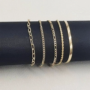 Detailed view of five gold-tone chain bracelets including paperclip and figaro styles