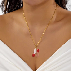 Dettaglio della collana dorata con ciondolo a capsula colorata a forma di lettera H