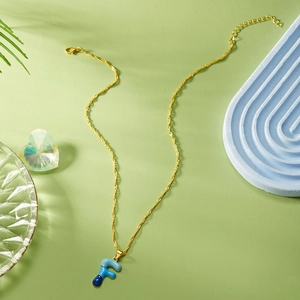 Dettaglio della collana con catena a onde dorata e pendente lettera F in smalto blu
