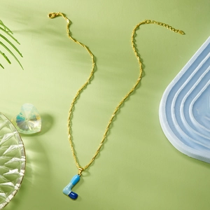 Dettaglio della collana dorata con ciondolo a lettera L in smalto blu