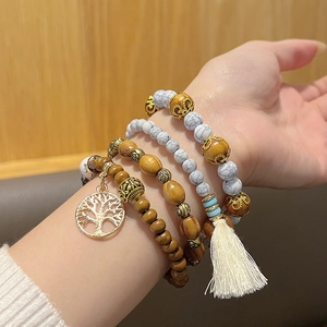 Détail de bracelets bohèmes à plusieurs rangs en bois avec arbre de vie et pompon
