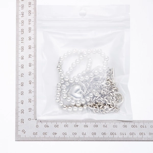Detail view of multilayer necklace with heart pendant and toggle clasp beside a metal ruler