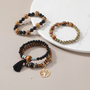 Détail de bracelets bohèmes en perles de bois avec breloque arbre de vie et pompon noir