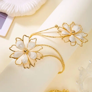 Vue détaillée d'un bracelet manchette lotus doré avec d'élégants pétales de fleurs blancs