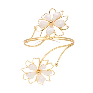 Gros plan d'un bracelet ouvert doré avec fleurs en nacre blanche et détails en métal martelé