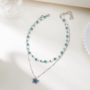 Detail of double-layer silver necklace with blue rhinestone butterfly pendant and crystal